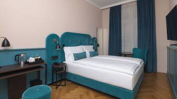Een hotelkamer met een groot bed, een bureau met een koffiezetapparaat, een stoel en een televisie.