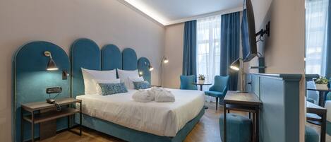 A modern hotel room with a large bed, bedside tables, a desk, and a chair.