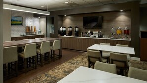 A modern hotel lobby with a bar area, seating, and a television mounted on the wall.