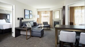 A hotel room with a bed, a sofa, a desk, and a chair.