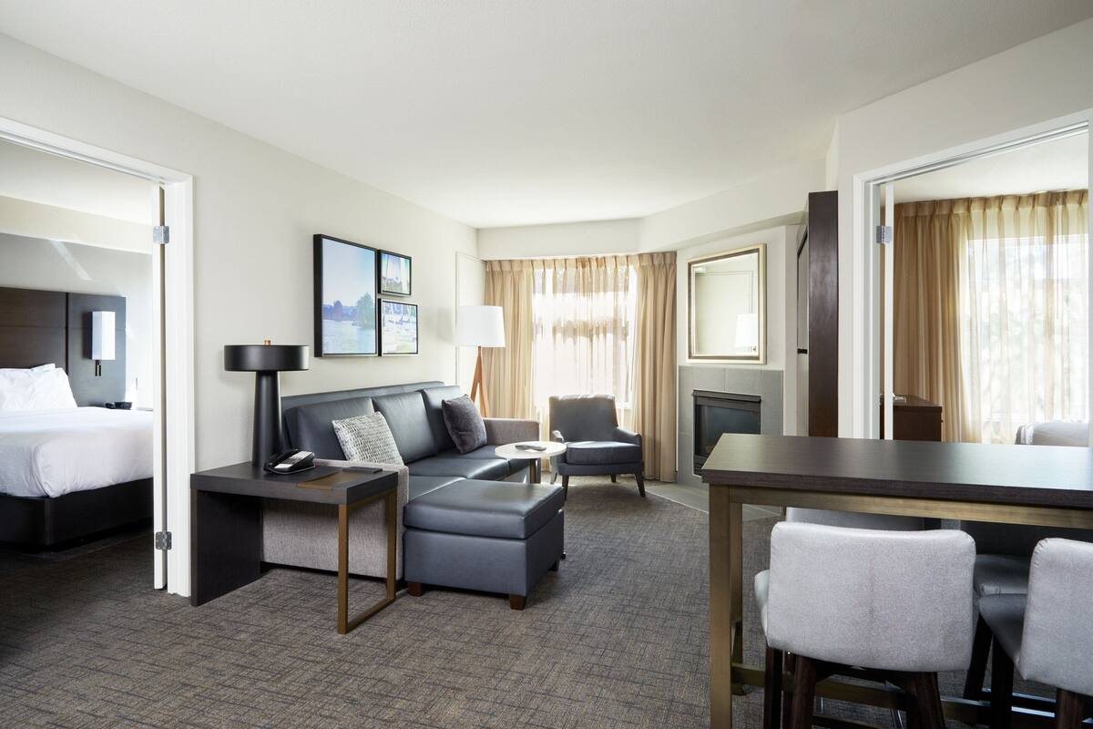A hotel room with a bed, a sofa, a desk, and a chair.