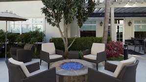 A circular seating area with a fire pit surrounded by wicker chairs.