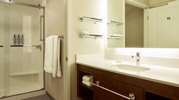A modern bathroom with a glass shower enclosure, a white sink, and a mirror above the vanity.