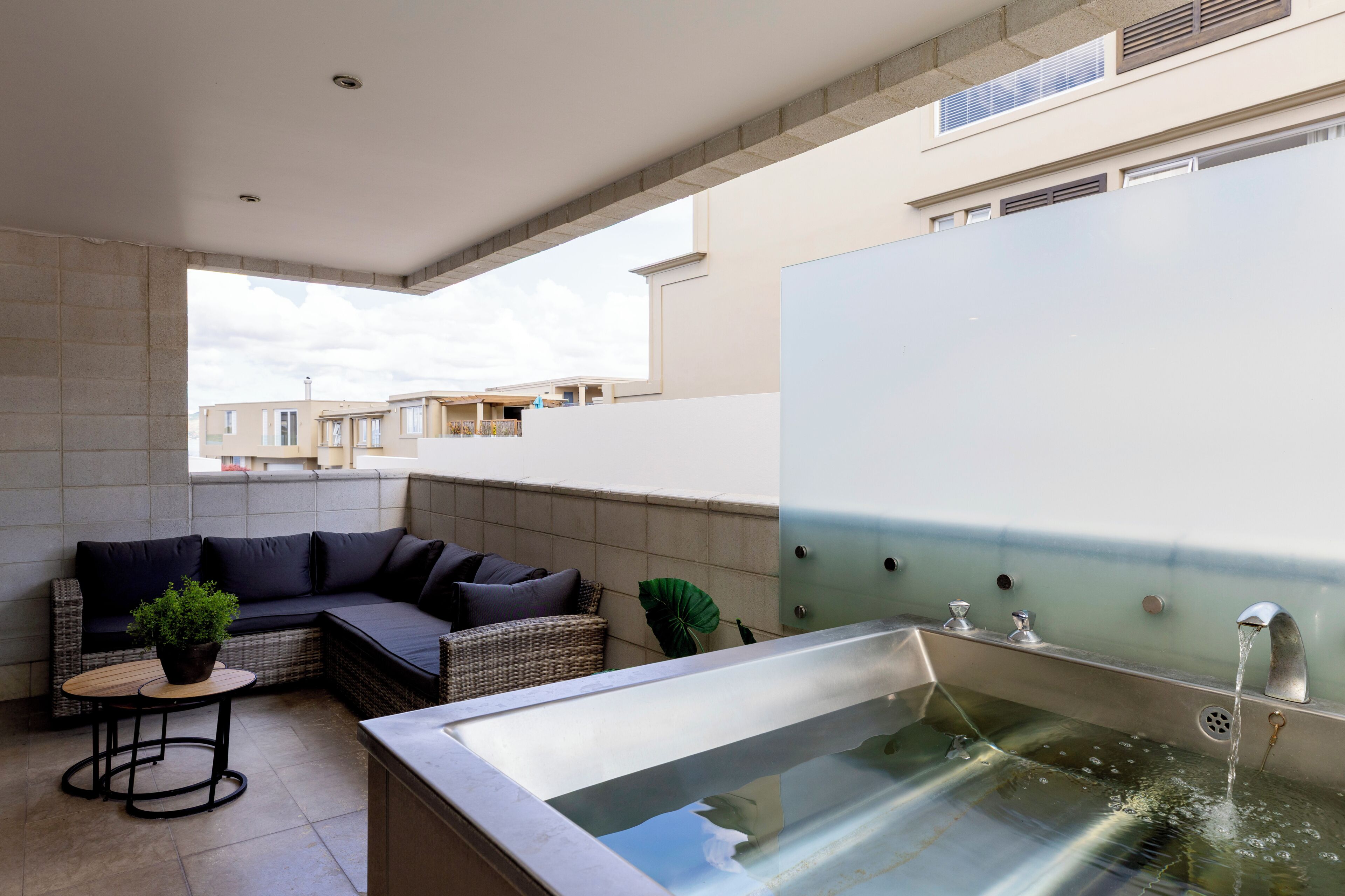 Una zona relax esterna moderna con un divano, un tavolino e una fontana.