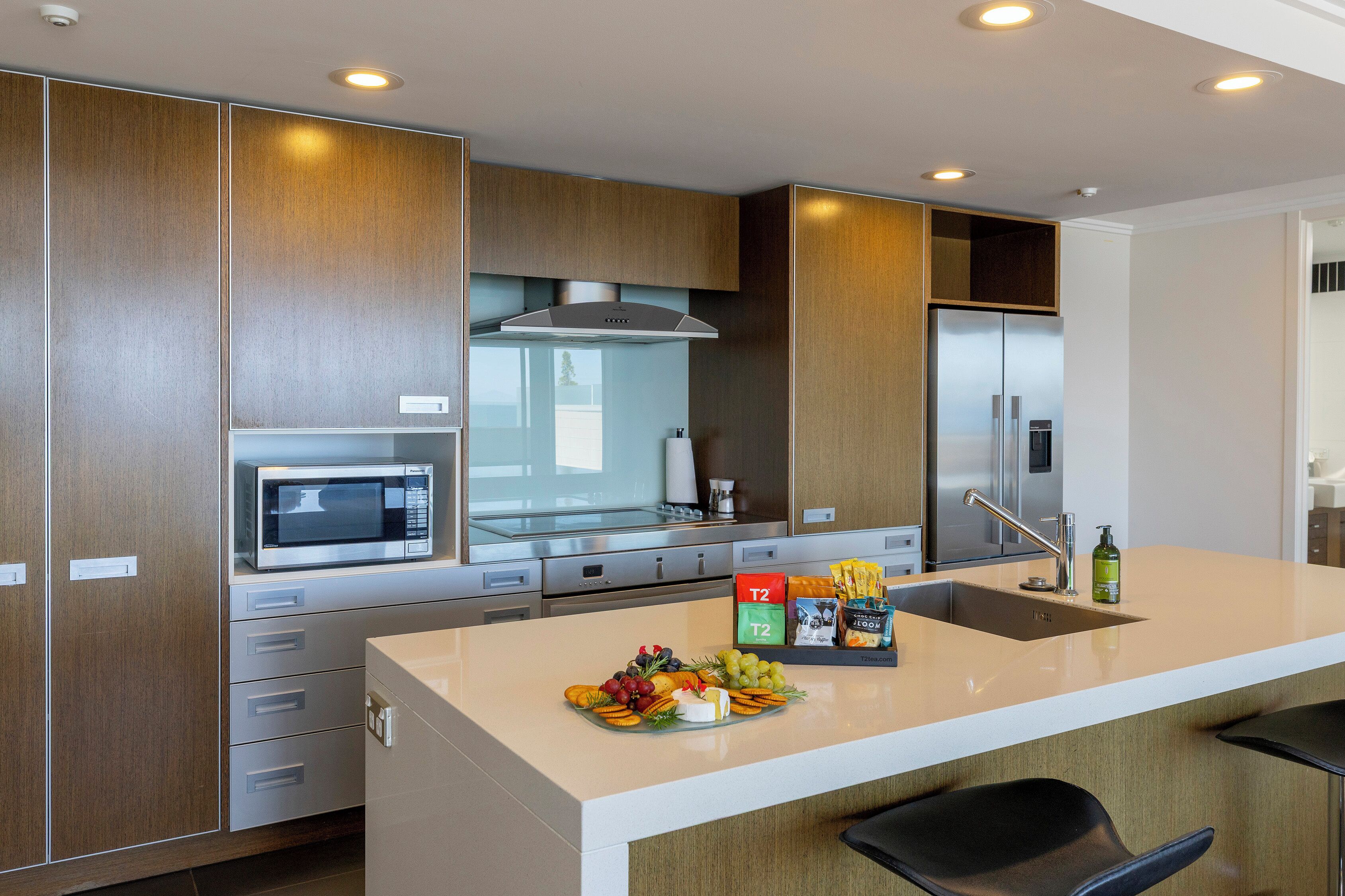 A modern kitchen with a central island, stainless steel appliances, and wooden cabinetry.