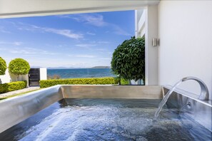 Un área de spa con hidromasaje, vistas al mar y un seto bien cuidado.