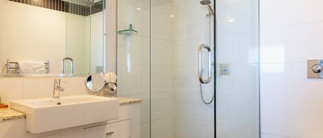A modern bathroom with a glass-enclosed shower, a white sink, and a large mirror.
