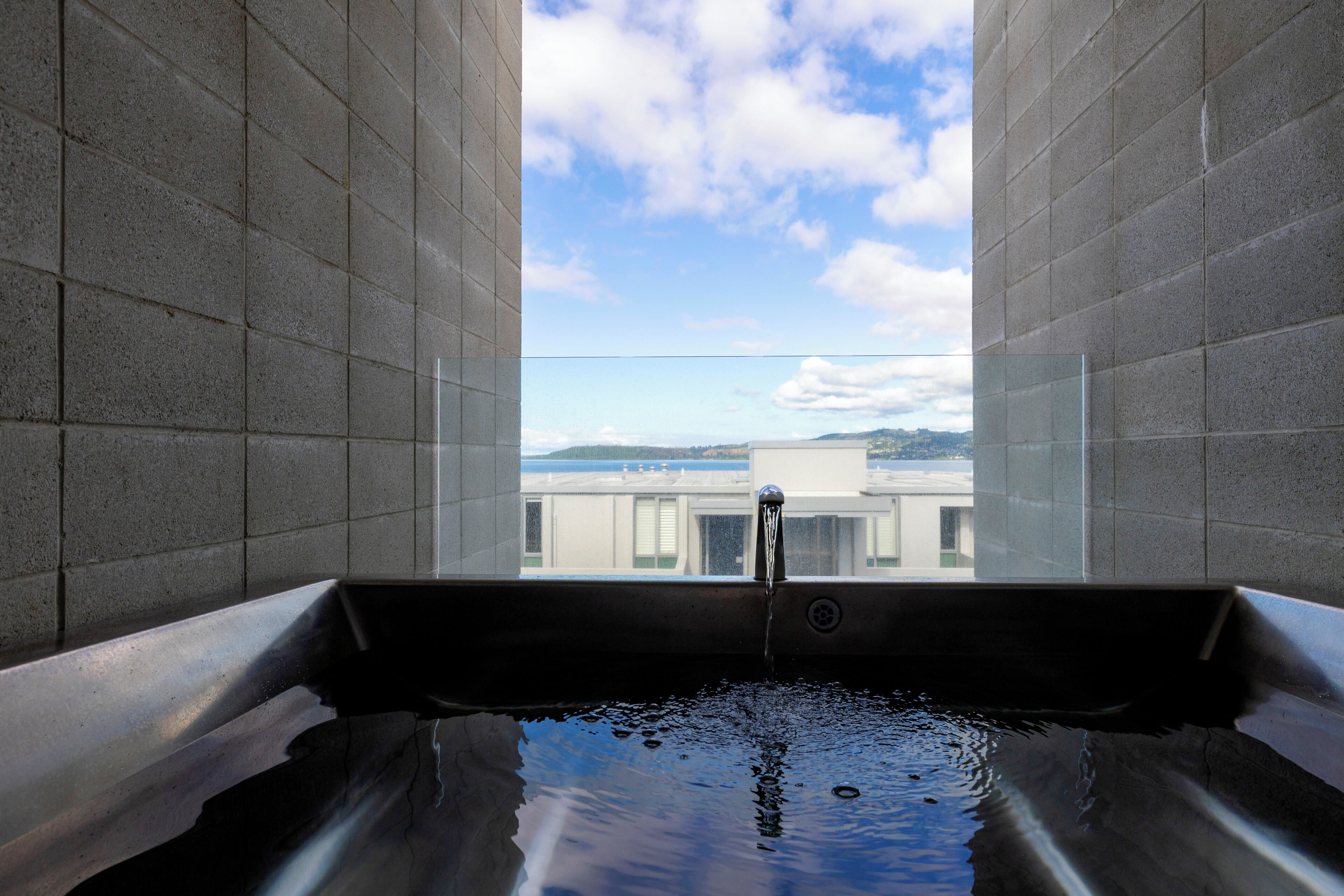 A bathtub with a view of buildings and a cloudy sky.