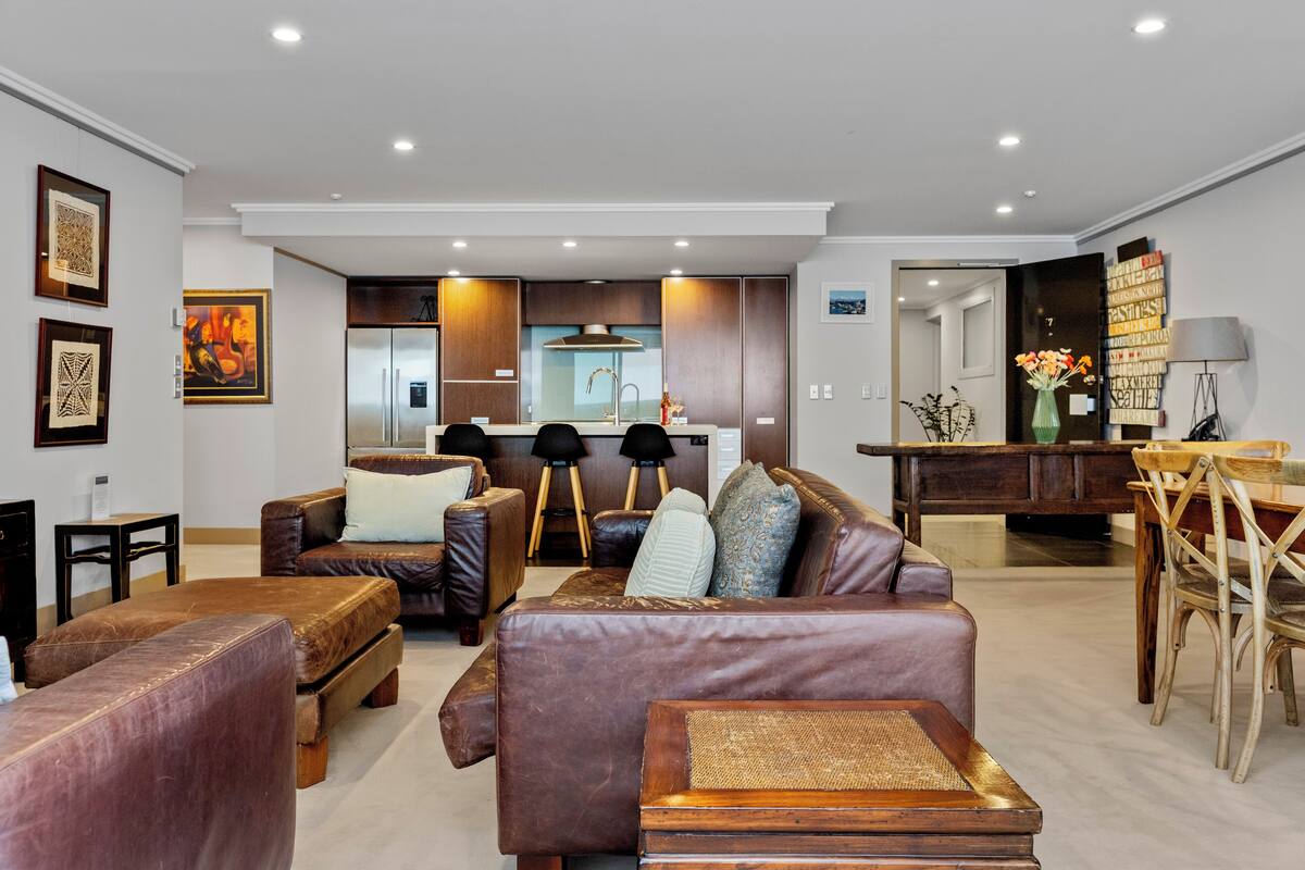 A modern living room with a sofa, ottoman, and dining area with chairs.