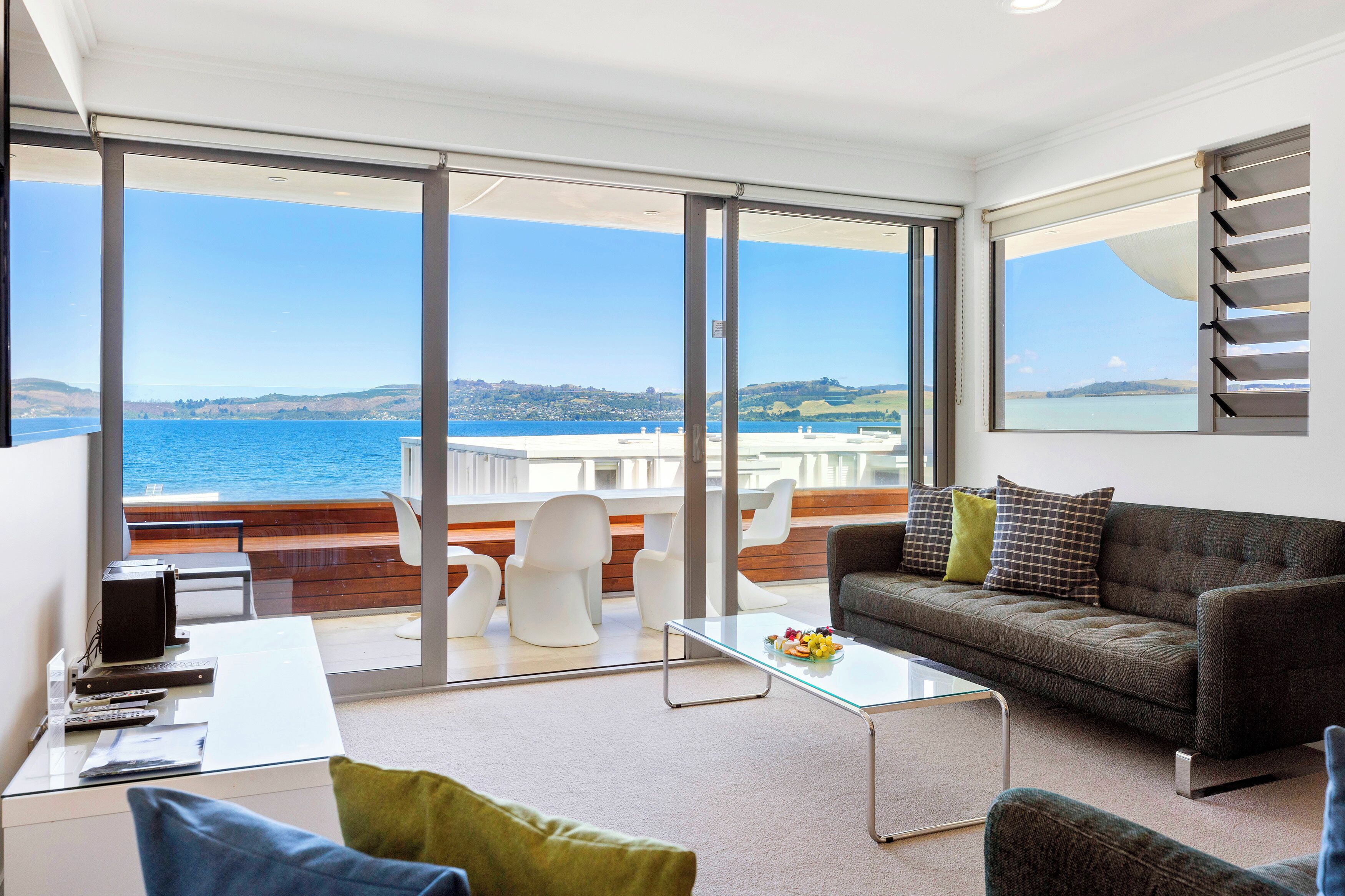 Un salon moderne avec une table basse en verre, un canapé et une vue sur la mer.