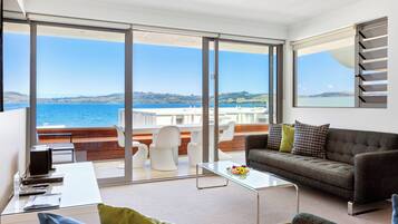 Un salon moderne avec une table basse en verre, un canapé et une vue sur la mer.