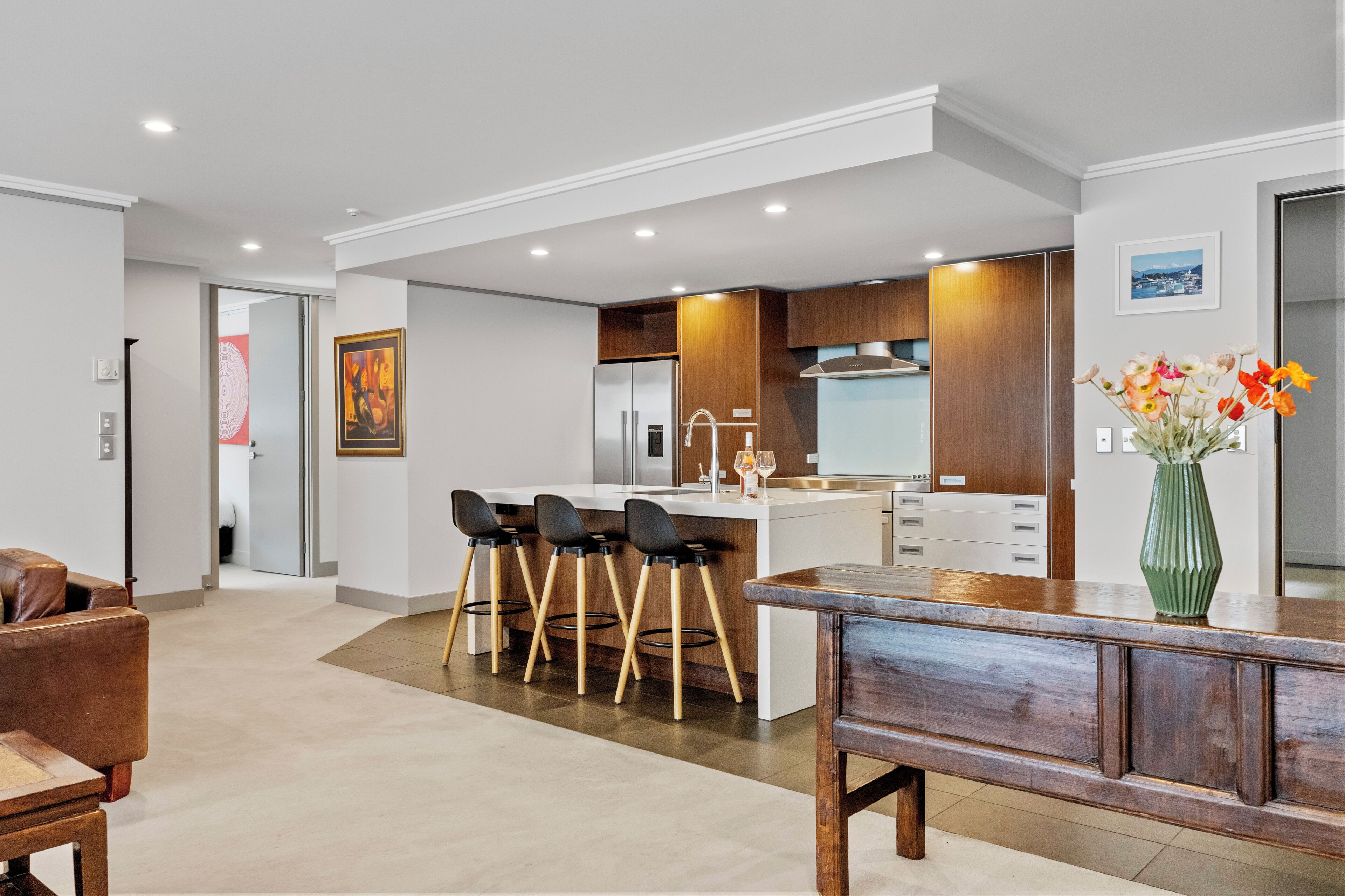 A modern kitchen with a central island, bar stools, and a dining table.