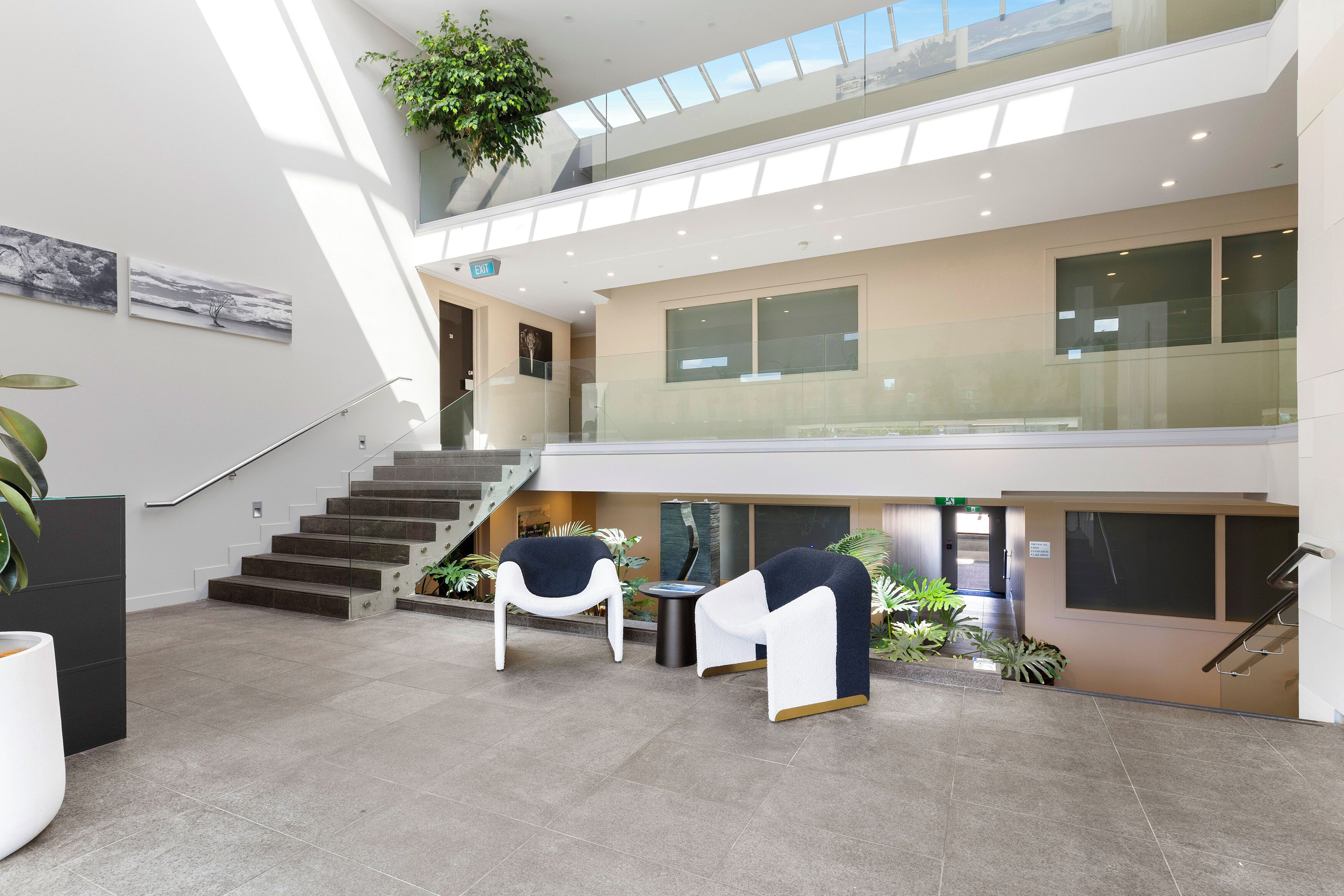 A spacious lobby with a staircase, seating area, and a large window.