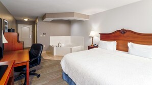 Une chambre d’hôtel comprenant un lit, un bureau, une chaise, une lampe de bureau, un téléphone, une table de chevet, une lampe et une baignoire.