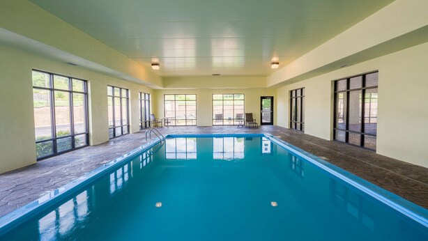 Une piscine intérieure avec des parois en verre transparent, un sol carrelé et un plafond doté d’un éclairage encastré.