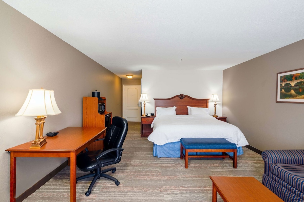 A hotel room with a bed, desk, chair, and a couch.