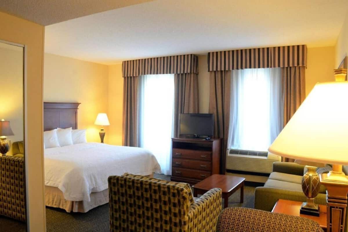 A hotel room with a bed, a television, a desk, a chair, and a lamp.