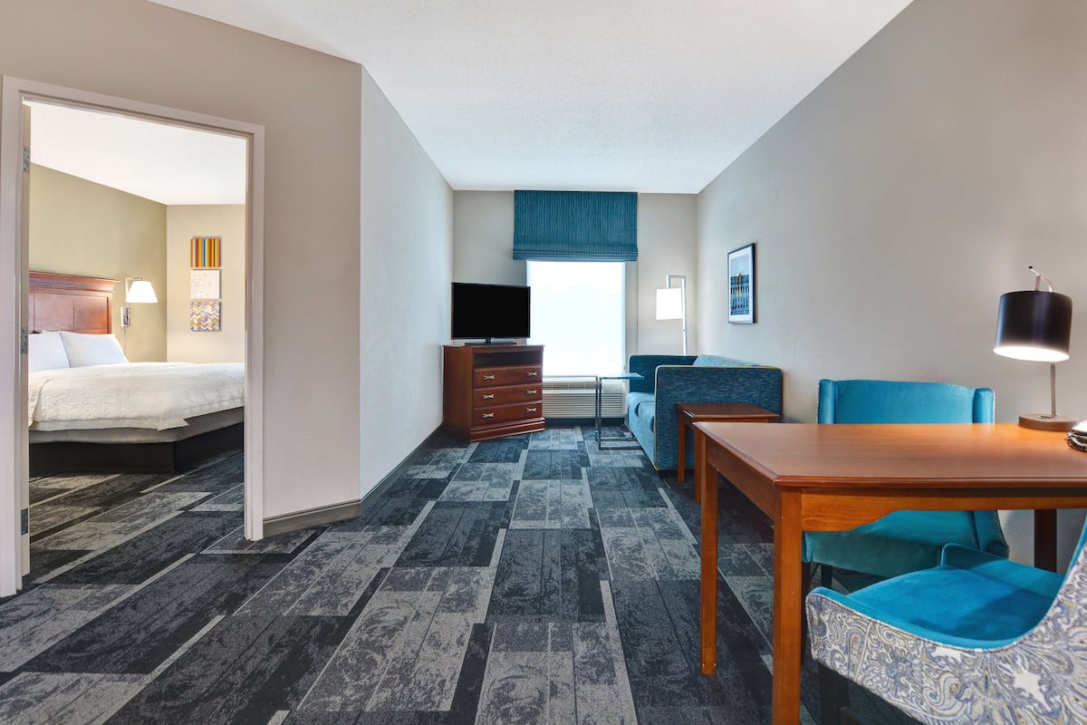 A hotel room with a bed, a desk, a chair, a television, and a window with a view.
