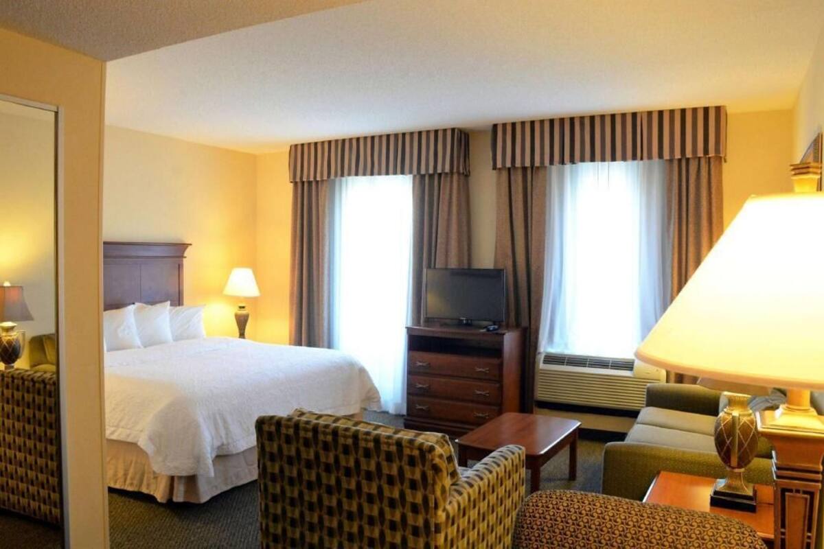 A hotel room with a bed, a television, a desk, a chair, and a lamp.