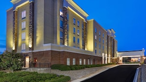 A multi-story hotel with a brick facade, large windows, and a well-lit entrance. - Hampton Suites Birmingham Hoover (Birmingham)