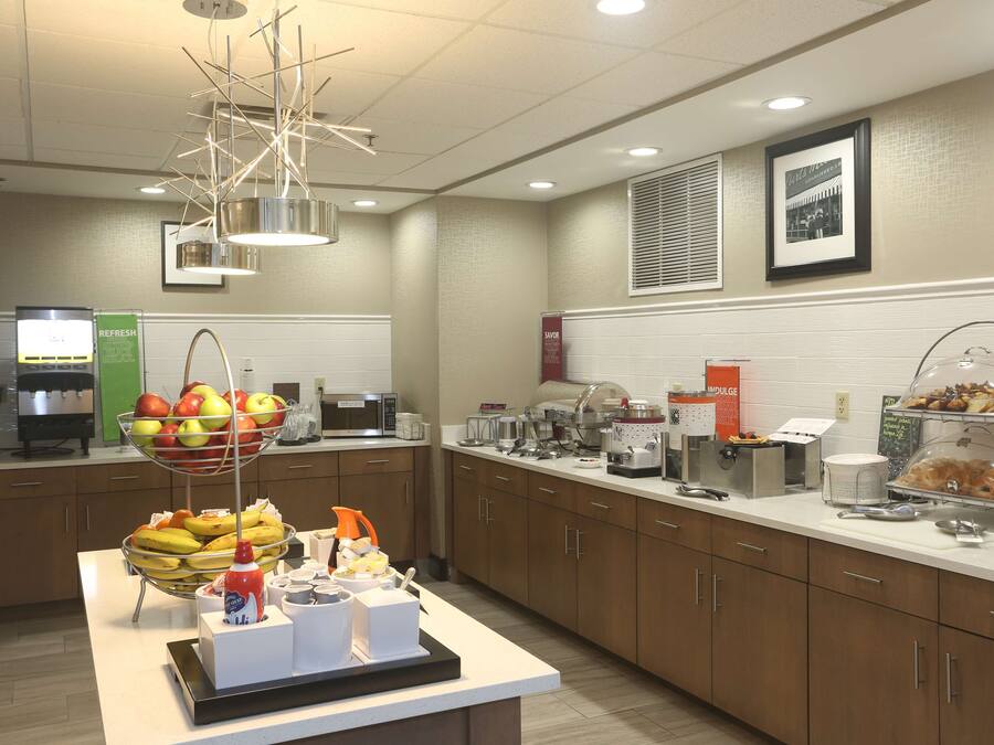 A buffet setup with a fruit bowl, coffee station, and various food items.