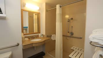 Un baño con lavamanos, espejo, ducha y toallero.