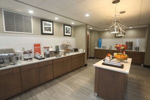 A modern kitchen with a long counter, coffee machines, and a fruit bowl.