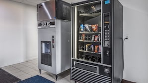 A vending machine with a freezer compartment and a drink dispenser, containing snacks and beverages. - Motel 6 McAlester, OK (Krebs)