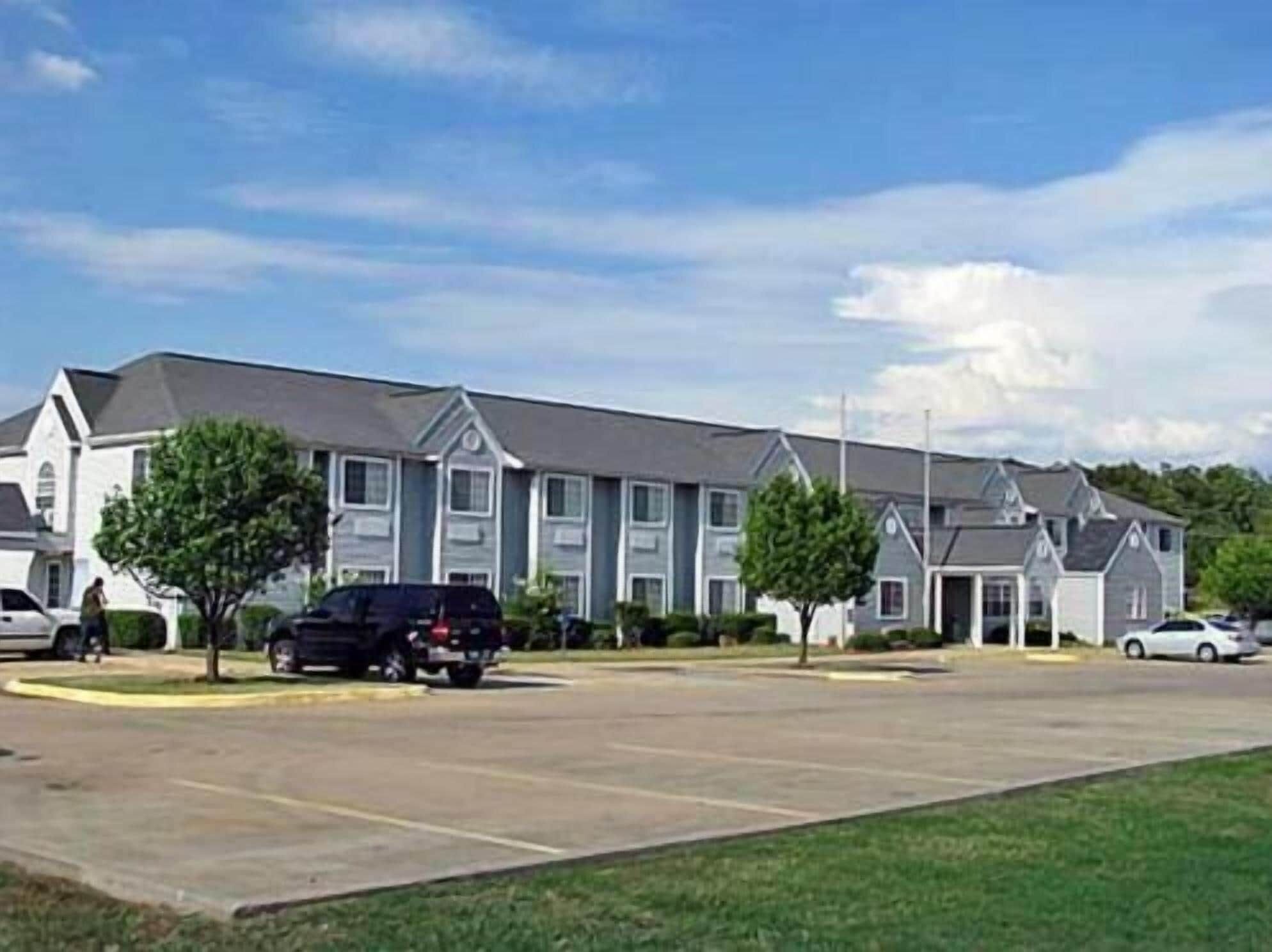 A row of two-story townhouses with a parking lot in front.