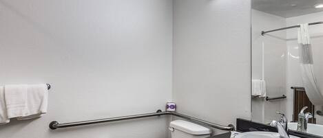 Un baño con inodoro, lavamanos, espejo y barandilla.