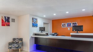 A reception area with a counter, two monitors, a printer, and a chair. - Motel 6 McAlester, OK (Krebs)