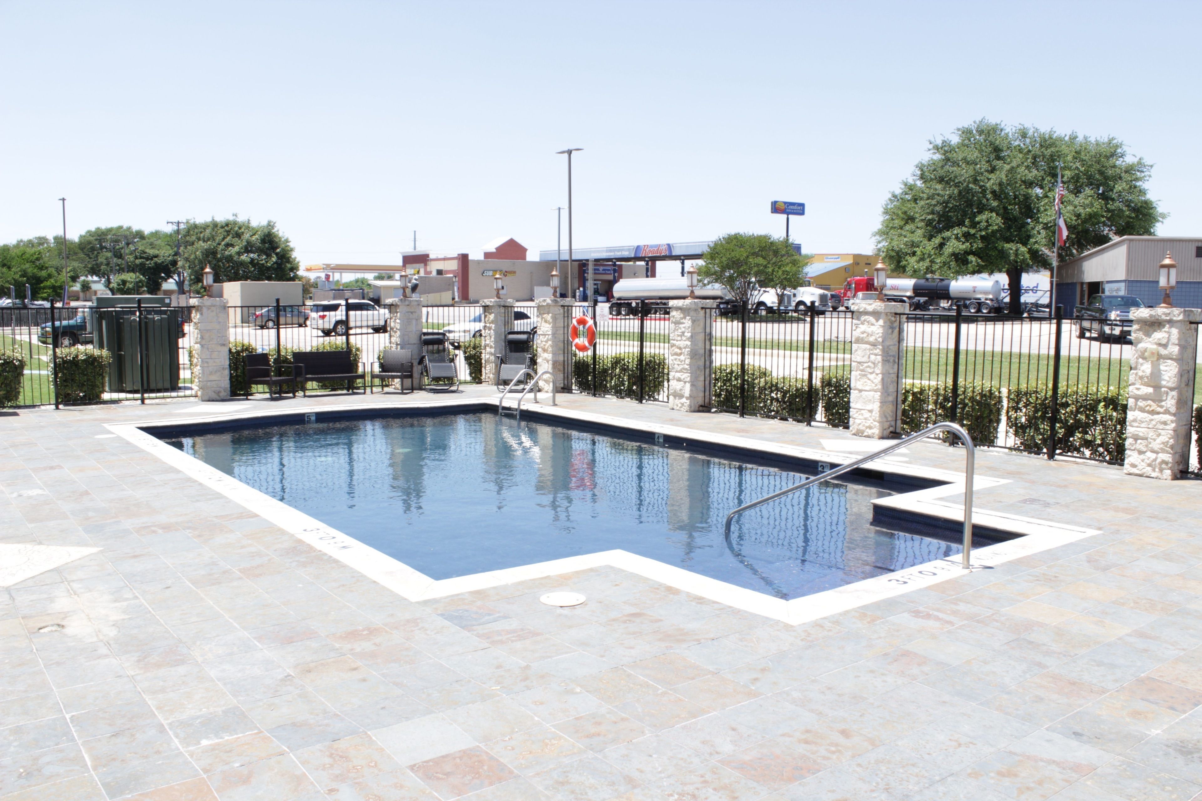 A rectangular swimming pool with a metal ladder and a stone border.