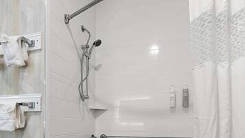 A modern bathroom with a walk-in shower, grab bars, a bathtub, and a glass-enclosed shower area.