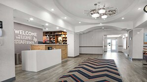 A hotel lobby with a reception desk, a welcome sign, and a modern chandelier. - Hampton Inn Seguin (Seguin)