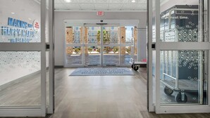 A hotel entrance with a modern design, featuring a glass door with a patterned design, a mat with text, and a view of the outside. - Hampton Inn Seguin (Seguin)
