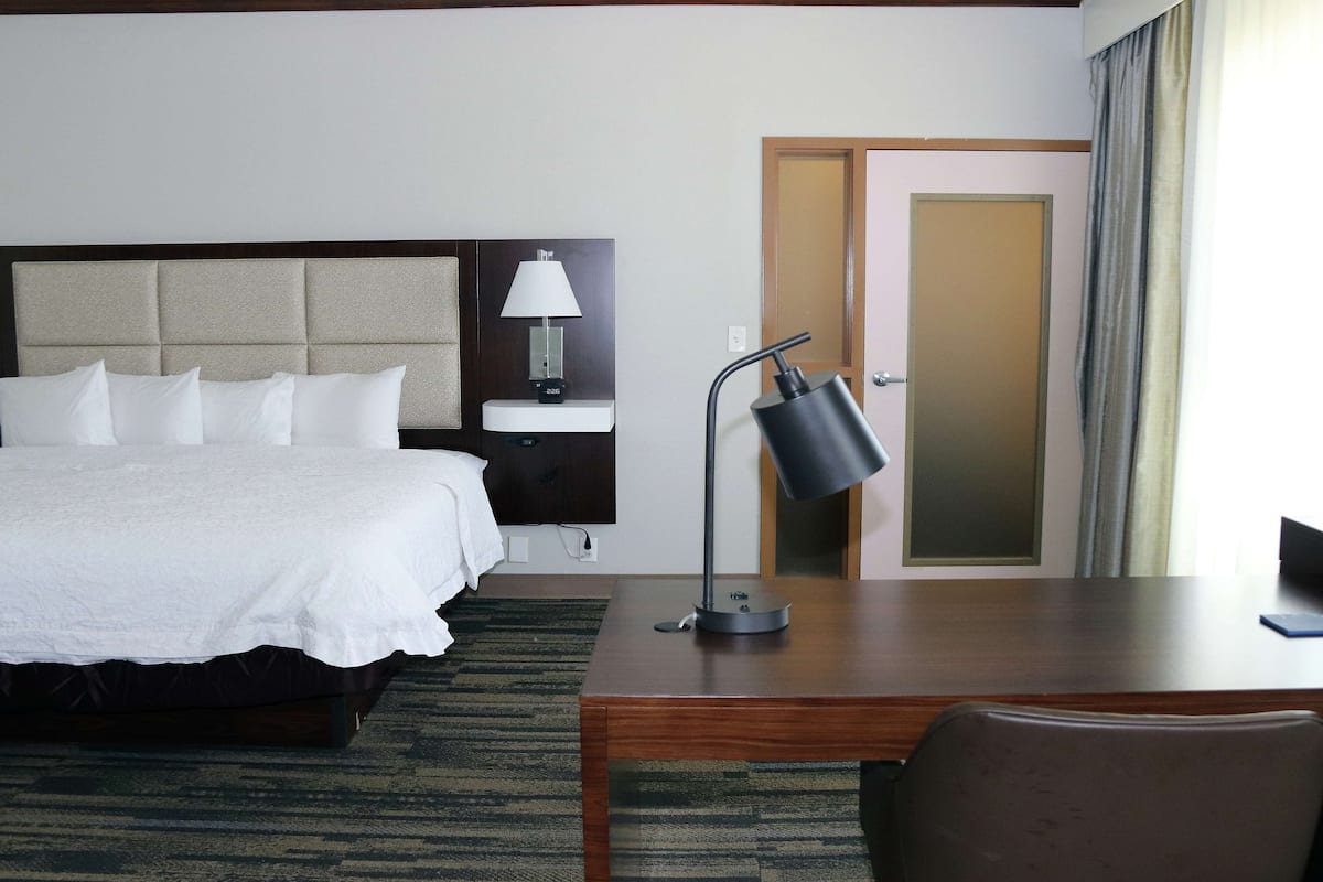 Una habitación de hotel con cama, mesita de noche, lámpara y escritorio con silla.