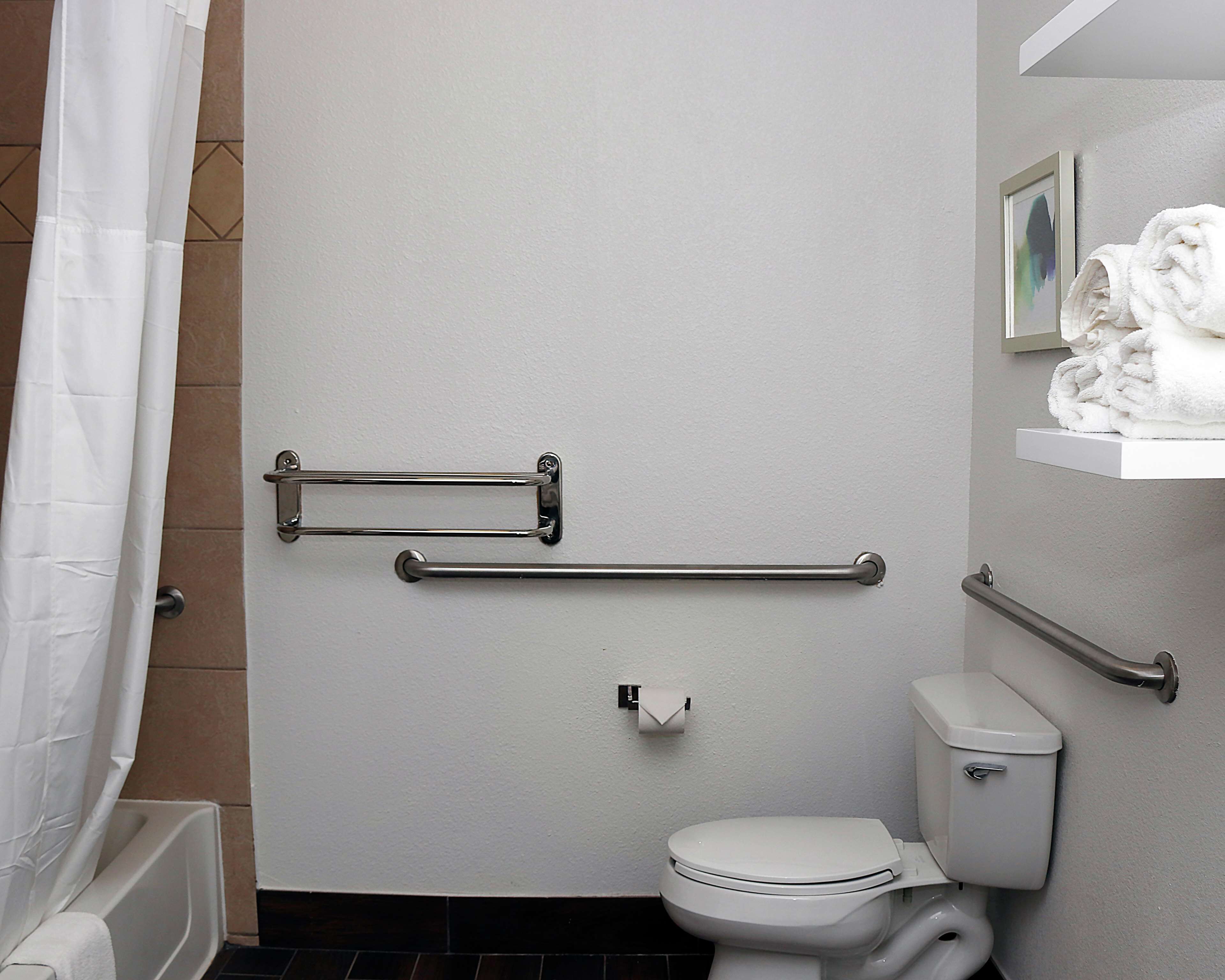 A bathroom with a toilet, a shower curtain, a towel rack, and a toilet paper holder.