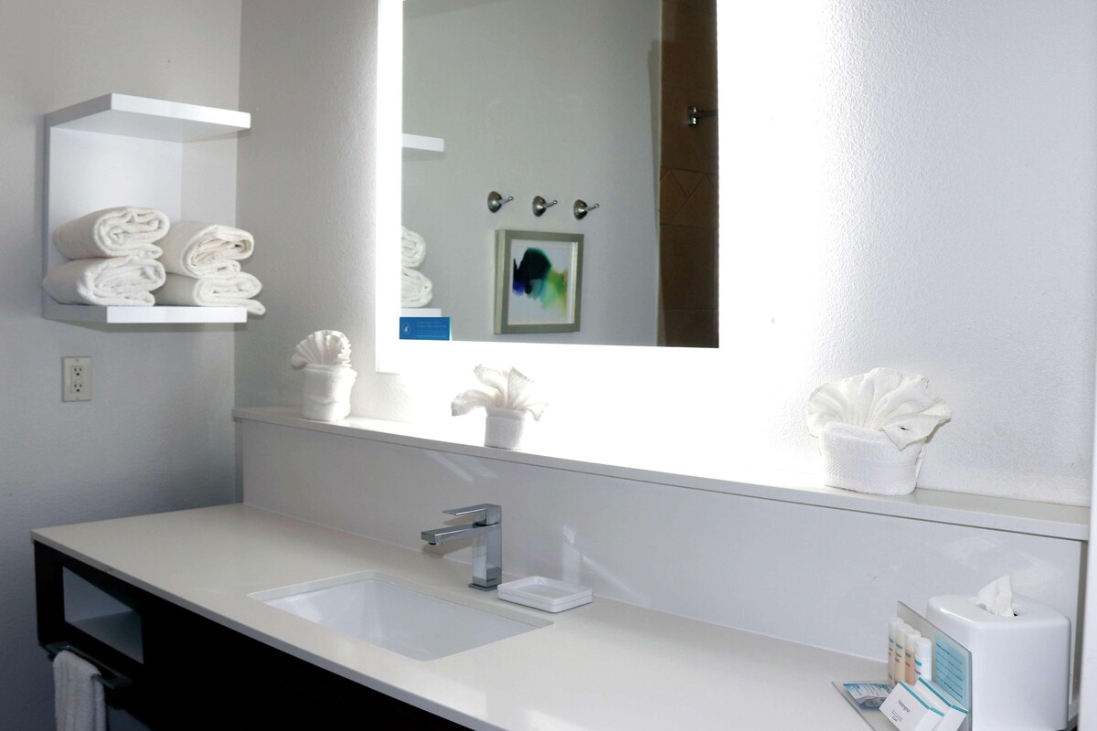 Un baño moderno con un lavamanos blanco, un espejo y un perchero para toallas.