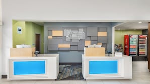A hotel reception area with two reception desks, a wall-mounted sign, and a Coca-Cola refrigerator. - Holiday Inn Express & Suites Spring Hill by IHG (Spring Hill)
