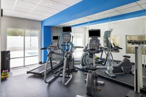 A gym with treadmills, exercise bikes, and a mirrored wall.