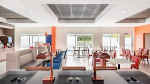 A modern restaurant with a mix of seating options, including booths and tables, and a large window providing a view of the outdoors. - Holiday Inn Express & Suites Spring Hill by IHG (Spring Hill)