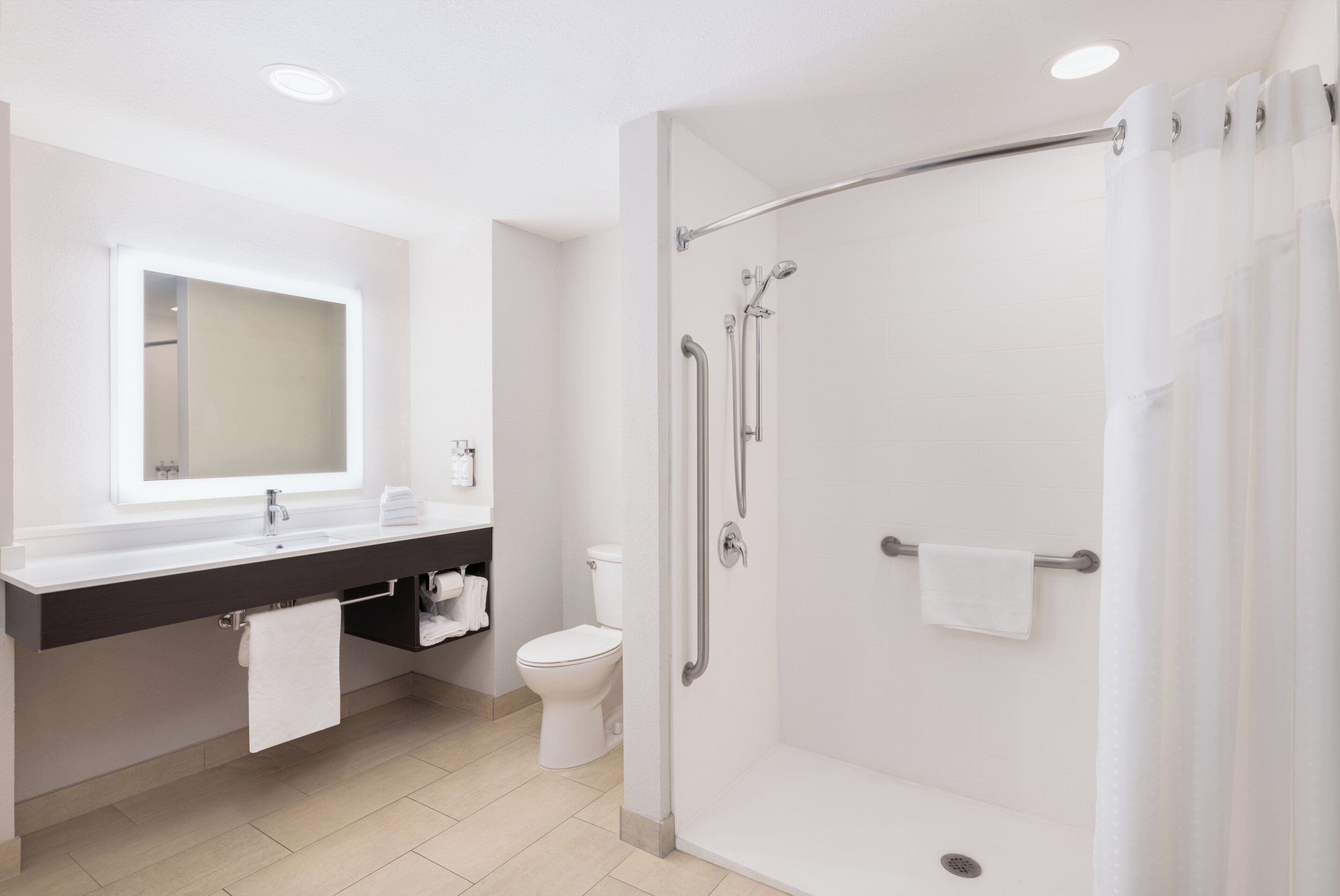 Un bany modern amb dutxa de vidre, un lavabo amb taulell fosc i un vàter.