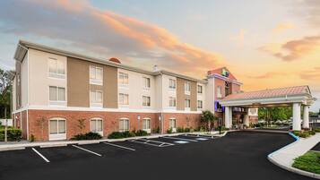 A hotel with a brick facade, a covered parking area, and a landscaped entrance.