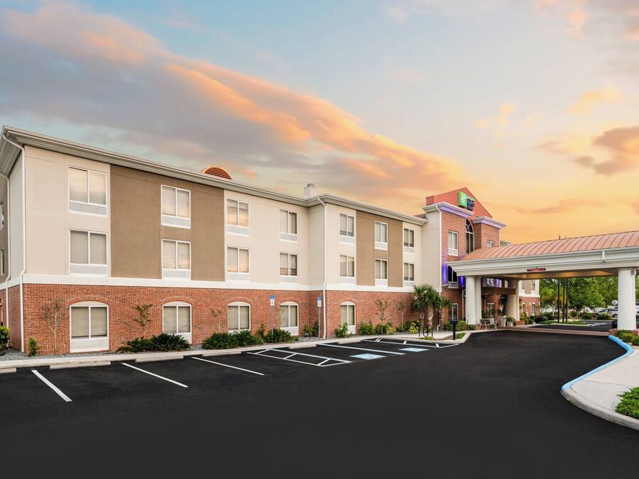 A hotel with a brick facade, a covered parking area, and a landscaped entrance.