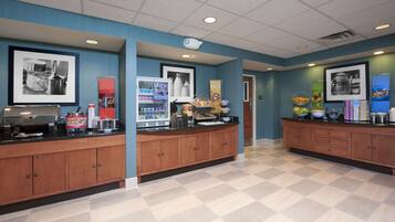 A breakfast area with a counter, coffee machine, and various food items.