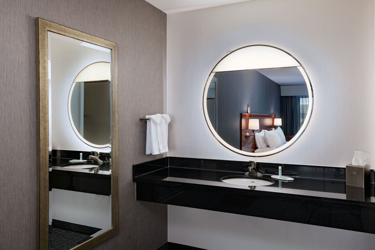 A modern bathroom with a large mirror, a sink, and a towel rack.