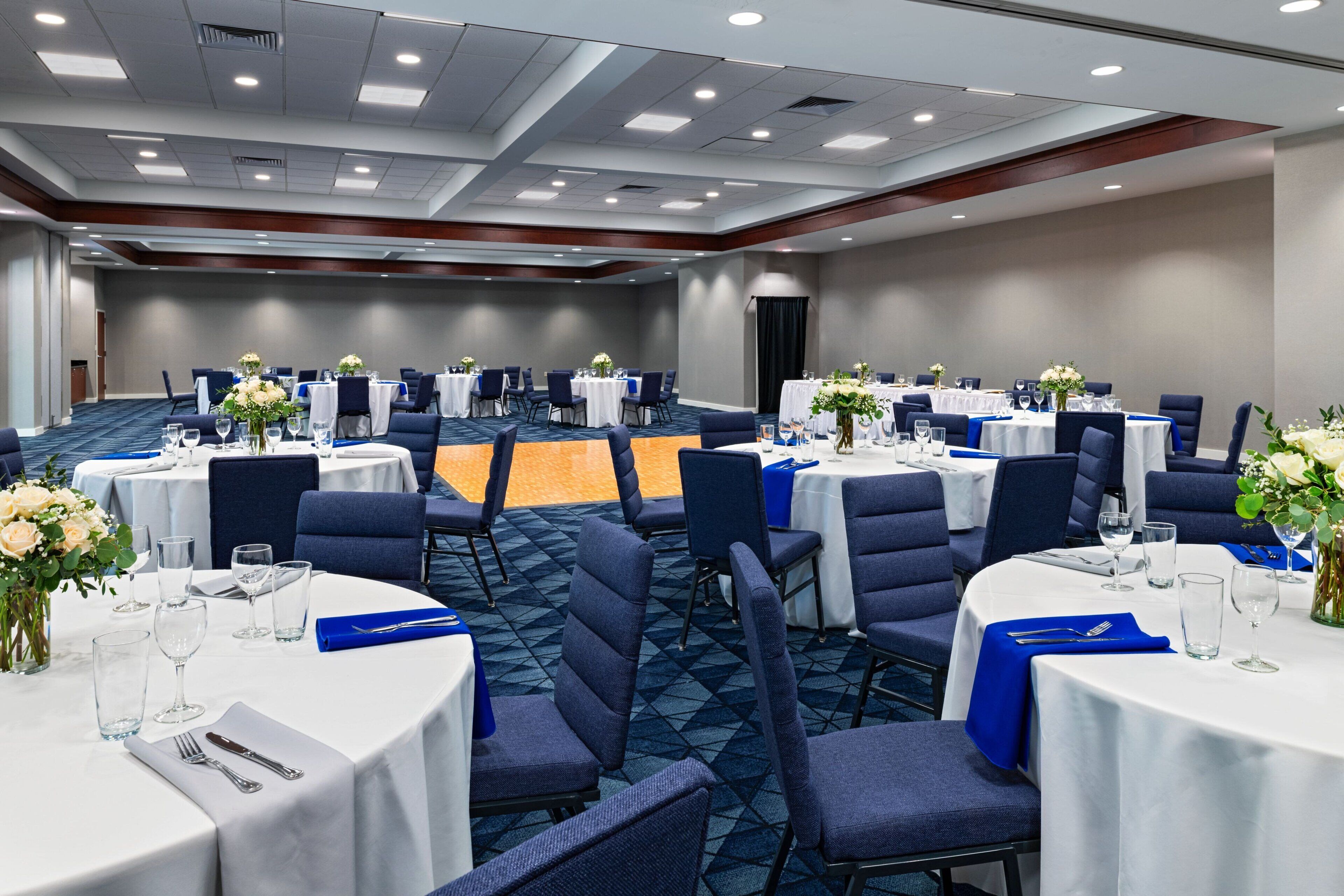 A conference room with round tables, chairs, and floral centerpieces.