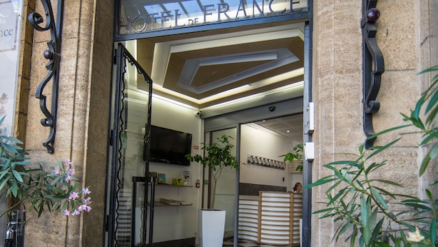 The entrance to Hotel de France with a checkered floor and a black doormat. - Hôtel De France (Aix-en-Provence)