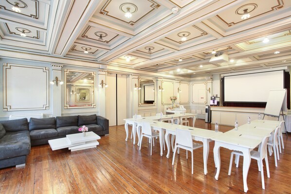 A conference room with a white table and chairs, a sofa, and a projector screen. - Hôtel De France (Aix-en-Provence)