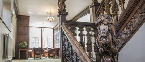 A grand staircase with intricate woodwork and a lion statue at the top.